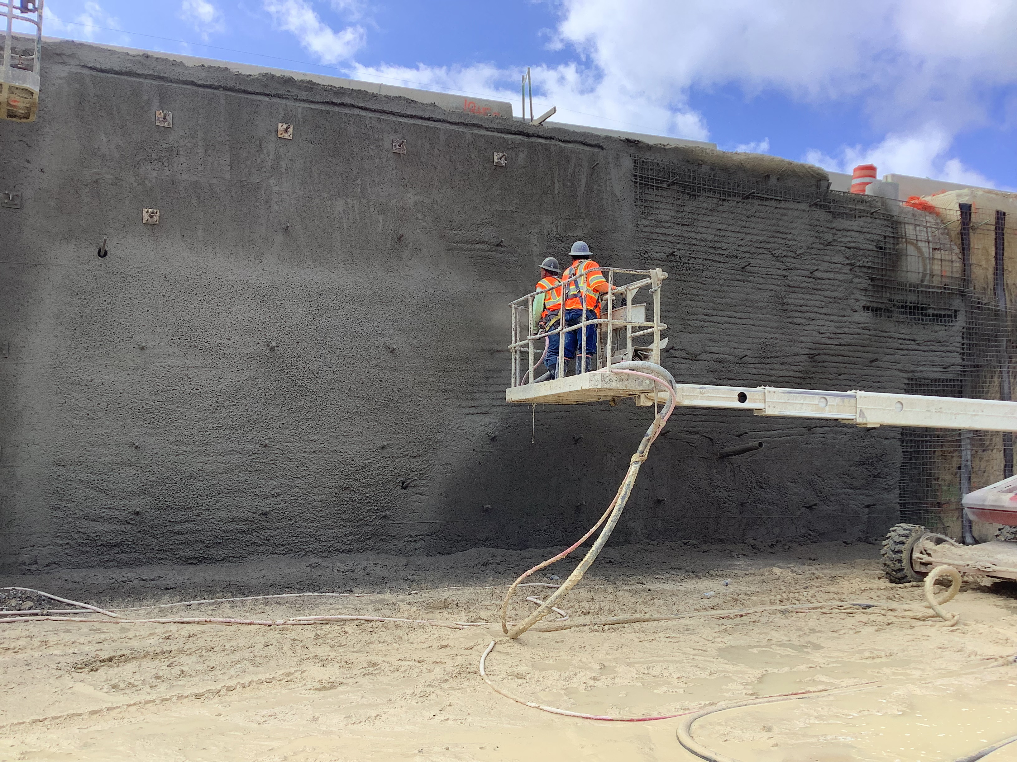 Crews add spray concrete to retaining wall.